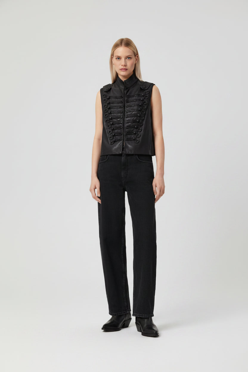 Person wearing a black sleeveless top with ruched details and black pants on a white background
