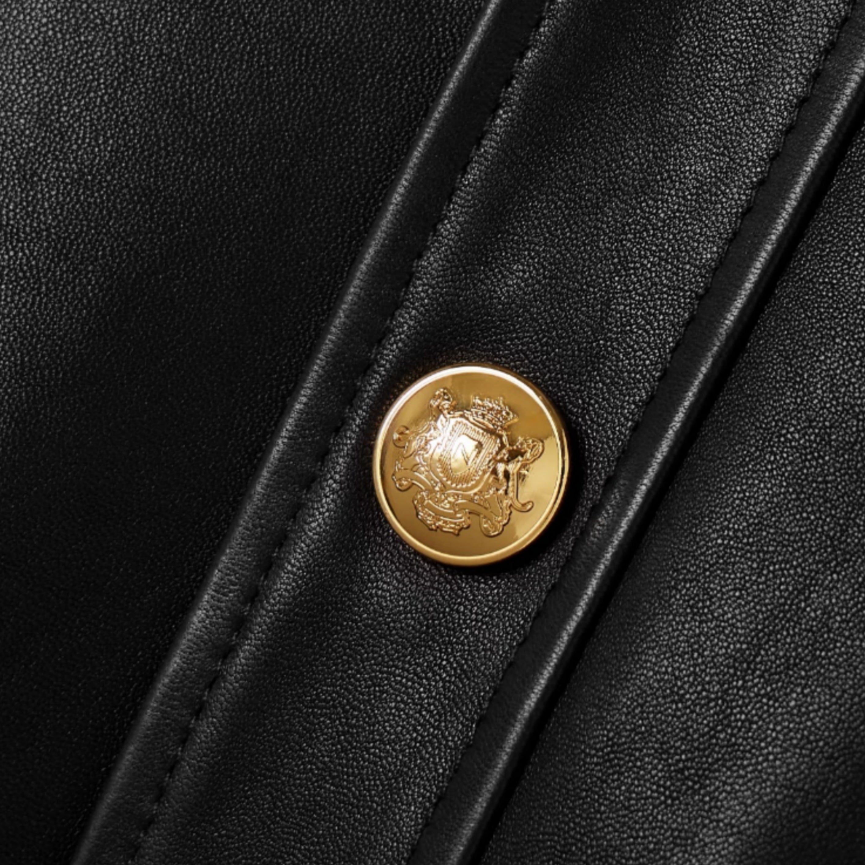 Gold button detail on women’s black leather jacket